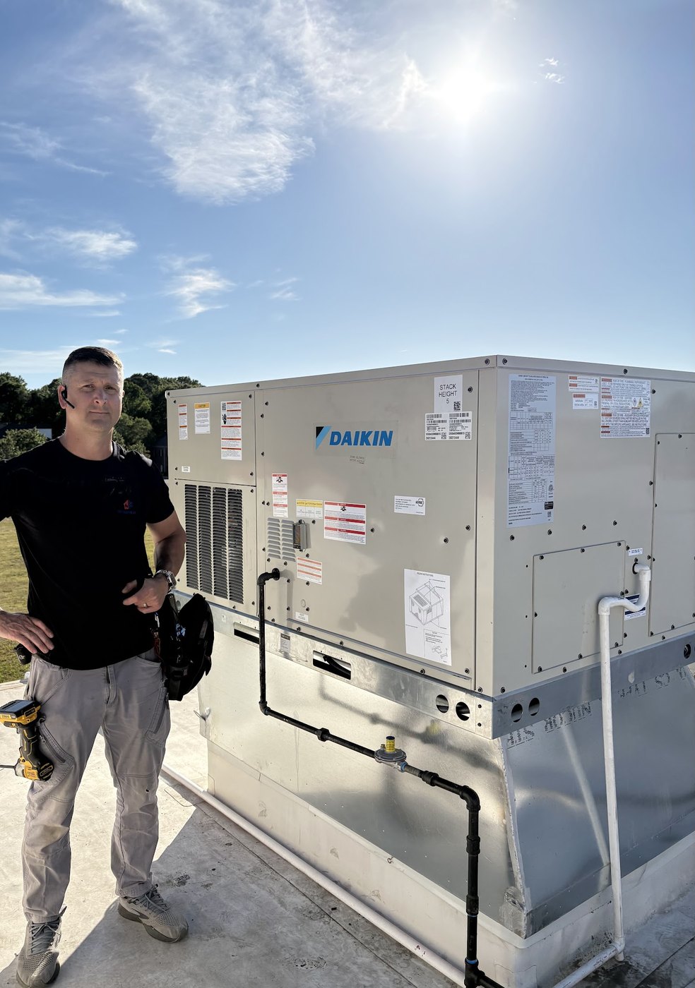 Sid's Heating and Air technician beside a rooftop packaged unit