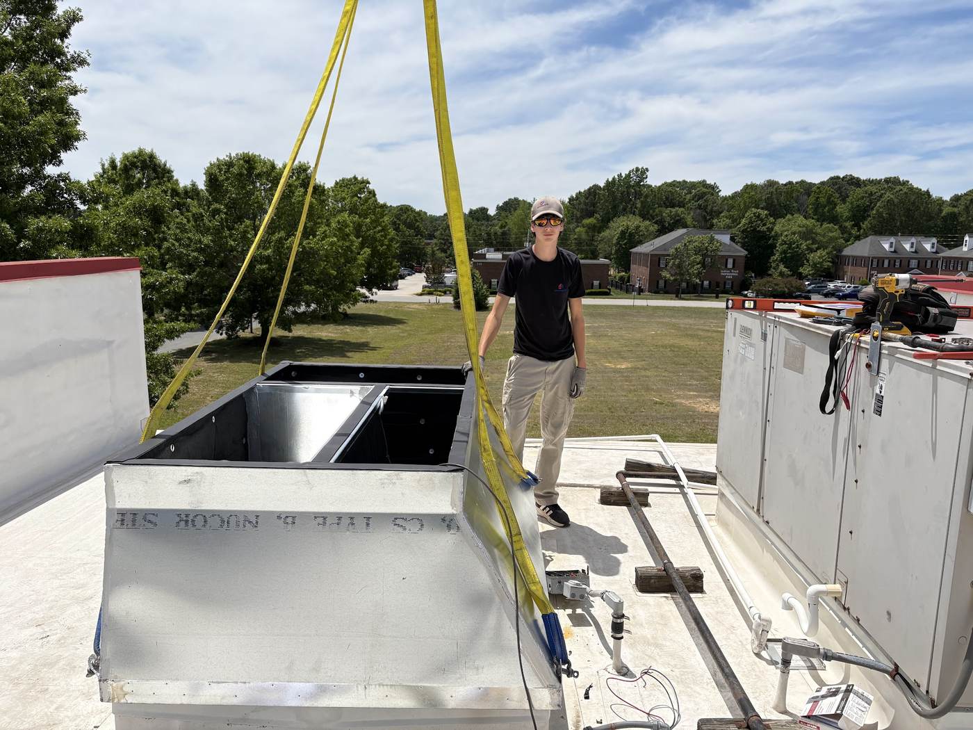Rooftop unit rigged with lifting straps during a commercial changeout