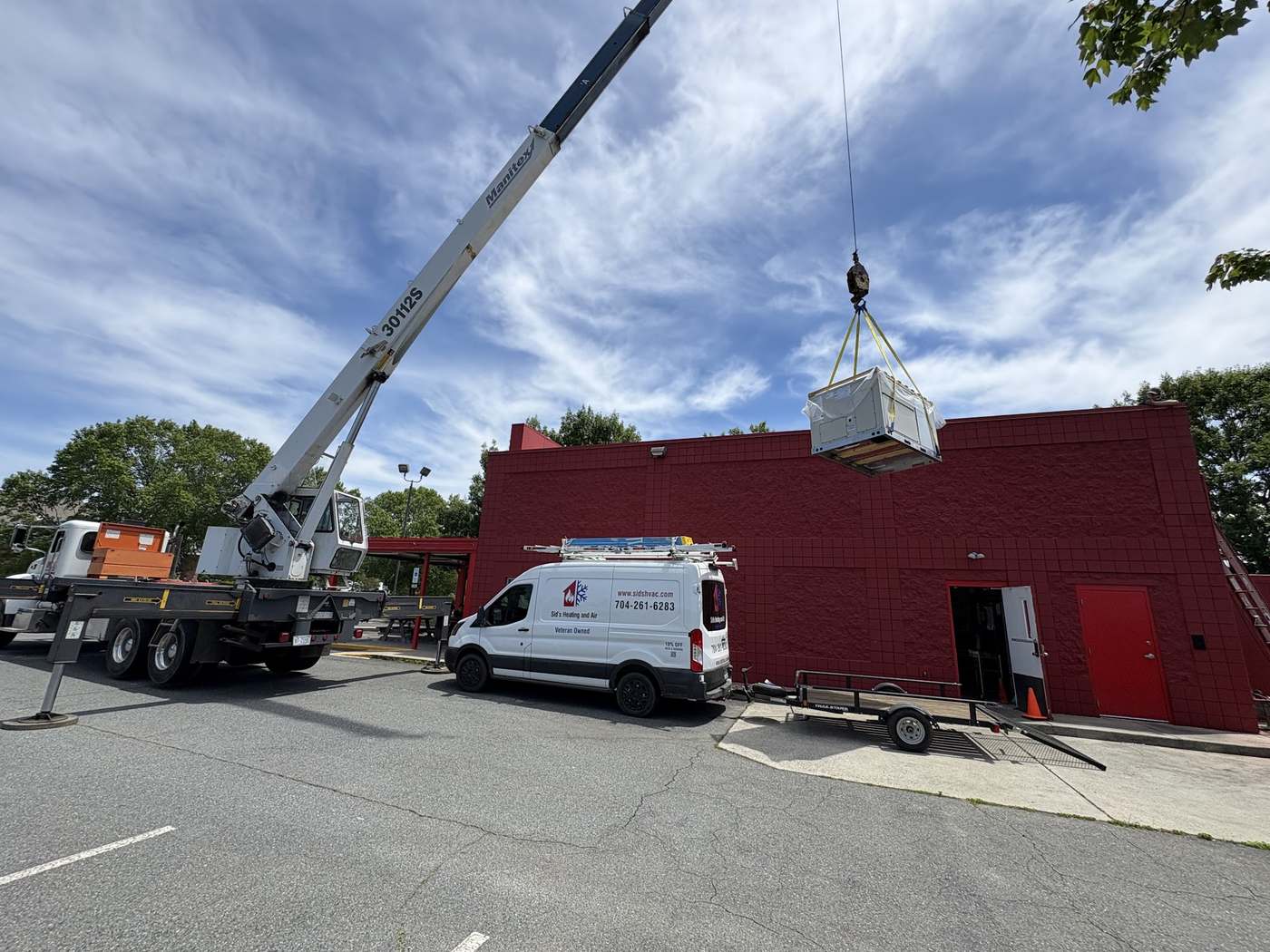 Crane lifting a packaged HVAC unit onto a commercial roof