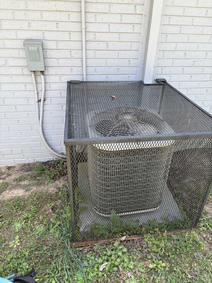 Residential AC condenser inside a protective security cage