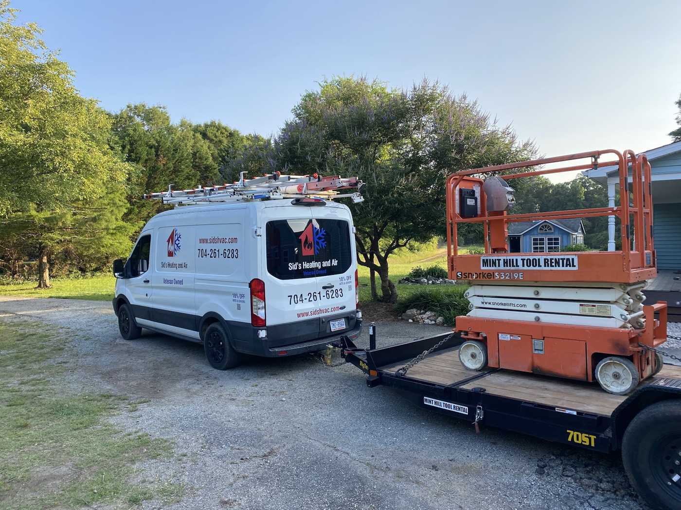 Service van and scissor lift trailered to a commercial job