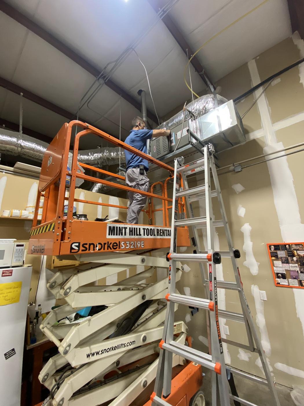 Overhead ductwork being serviced from a scissor lift