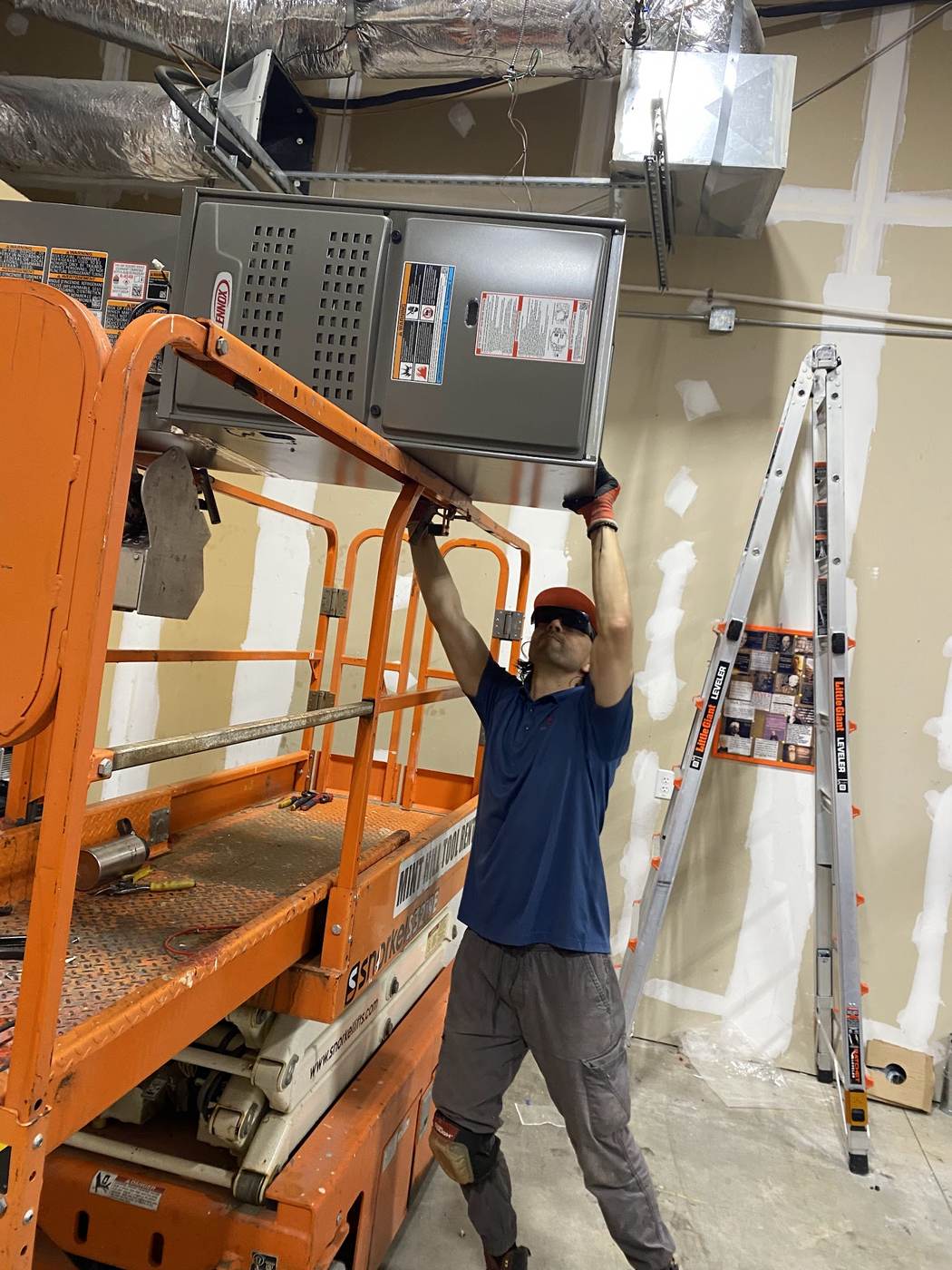 Sid's Heating and Air technician working from a scissor lift on an electrical panel