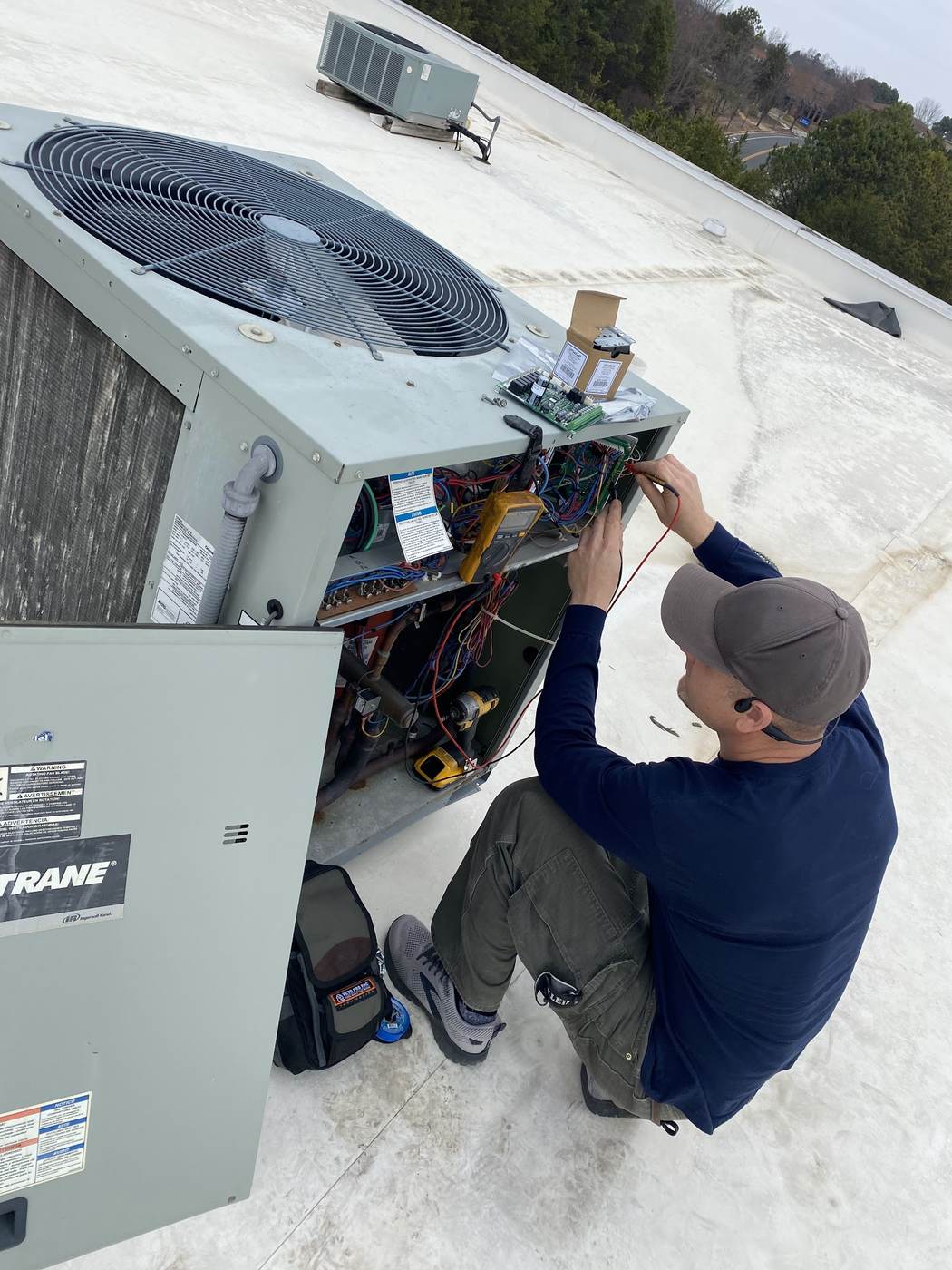 Technician diagnosing the electrical side of an outdoor condensing unit