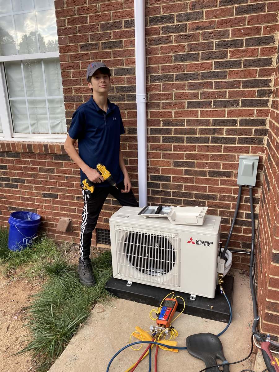 Technician beside a newly installed ductless mini-split outdoor unit