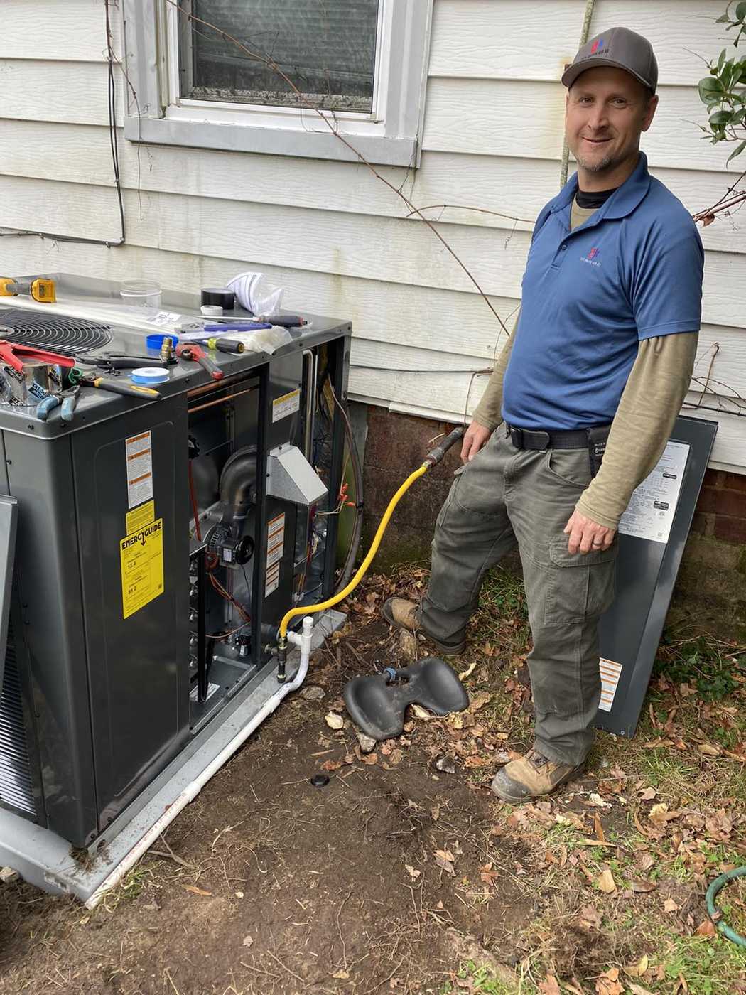 Sid's Heating and Air technician beside an open packaged unit