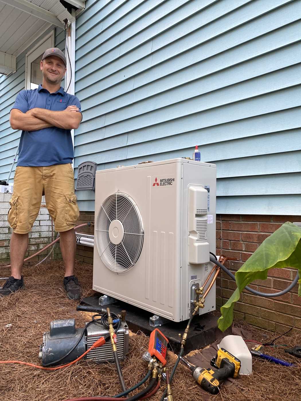 Technician beside a completed ductless mini-split installation