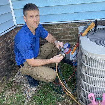 Technician on manifold gauges at a residential condenser