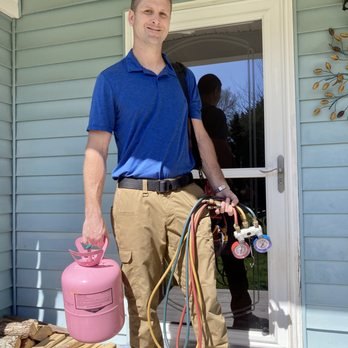 Technician carrying refrigerant recovery equipment to a job